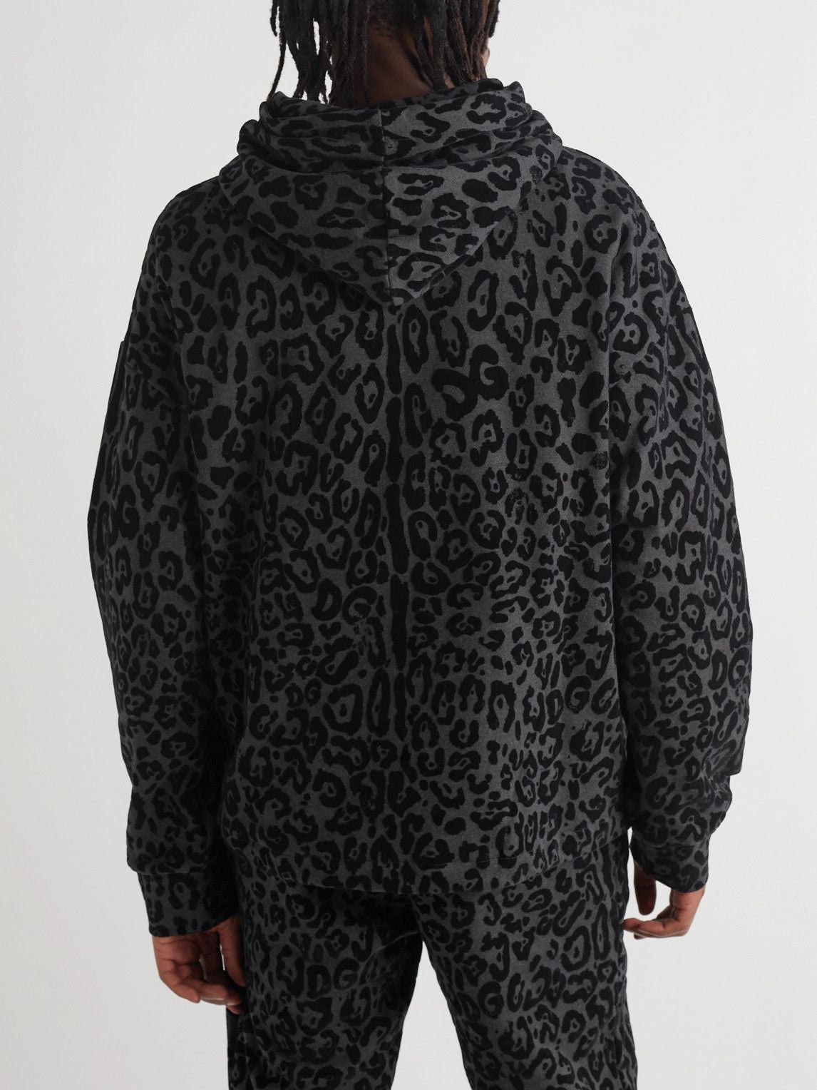 Person wearing a dark gray leopard print hoodie on a white background
