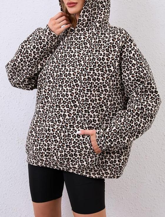 Person wearing a leopard print hoodie against a white background