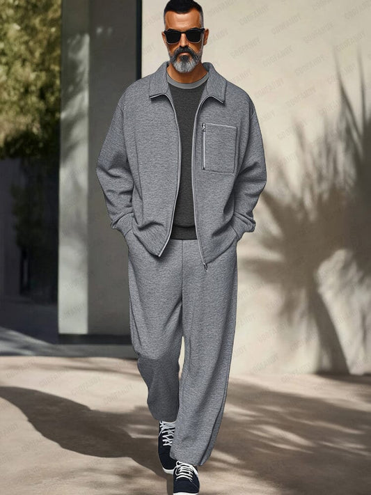 Man wearing a gray tracksuit with sunglasses walking outdoors.