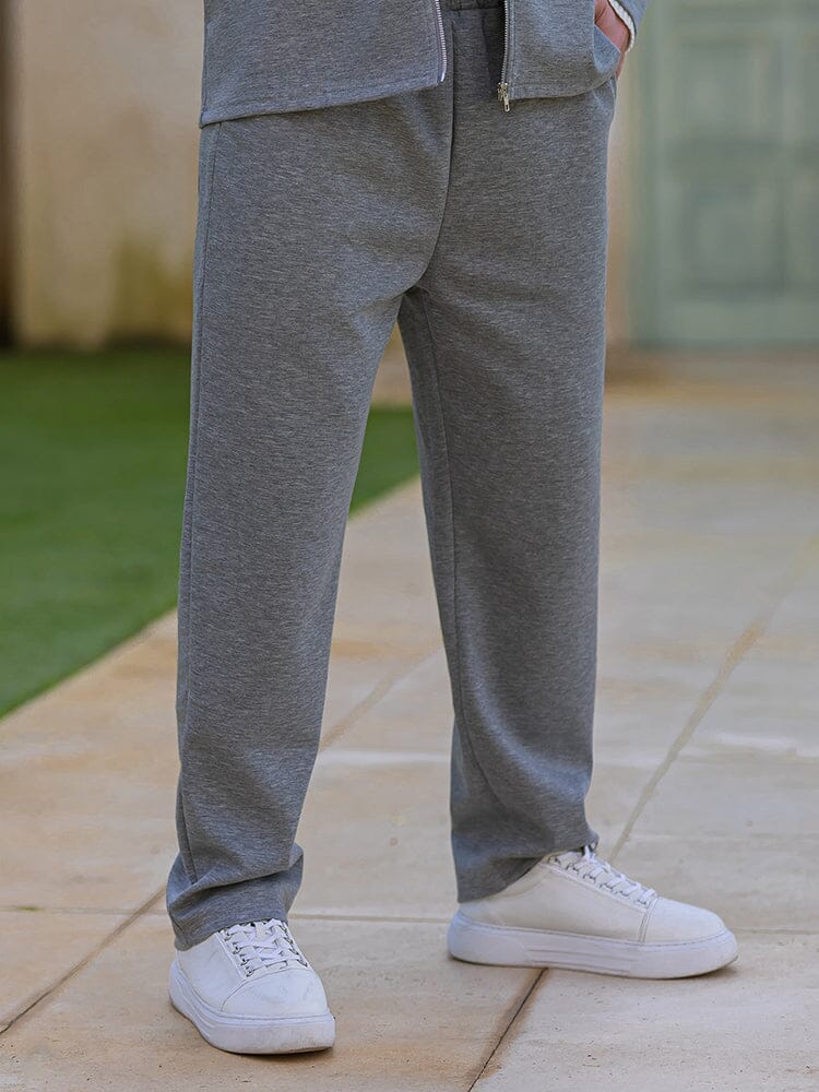 Person wearing gray sweatpants and white sneakers on a stone path.