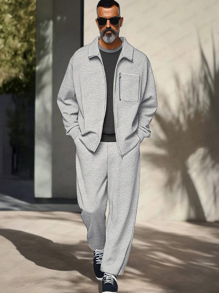 Man wearing a gray tracksuit with sunglasses walking outdoors.