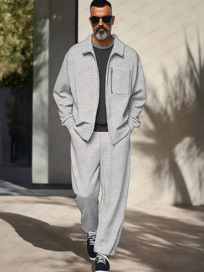 Man wearing a gray tracksuit with sunglasses walking outdoors.
