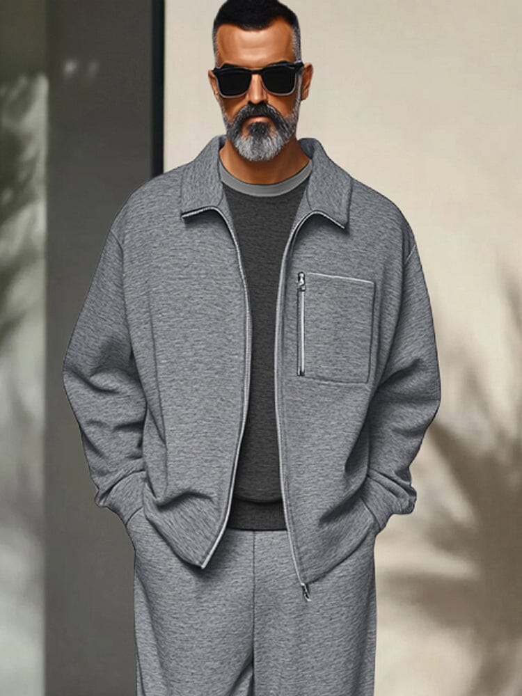 Man wearing a gray outfit with sunglasses against a neutral background