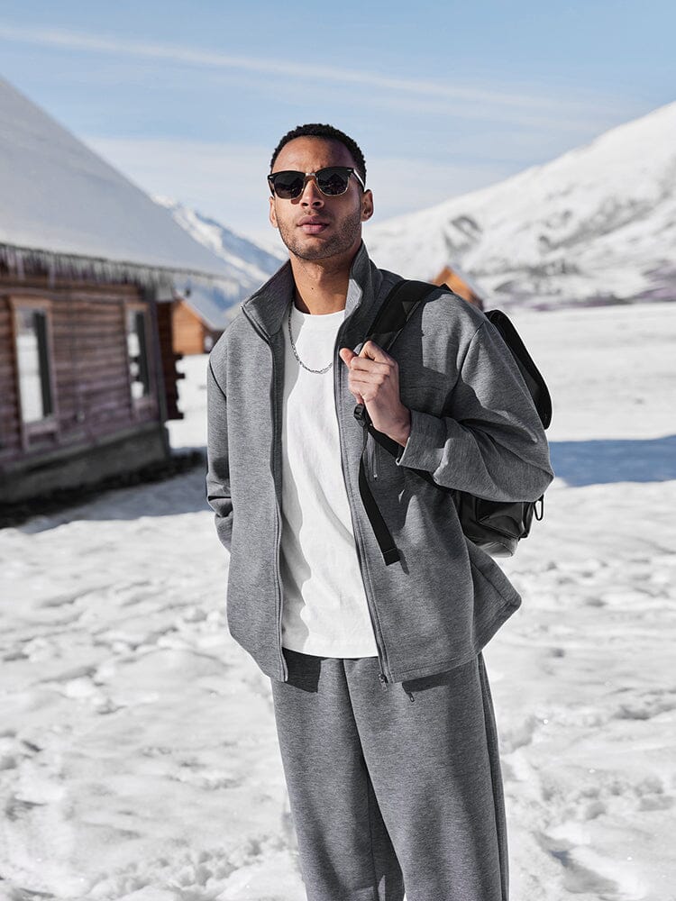 Man in gray outfit with sunglasses standing in a snowy landscape