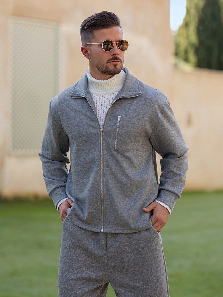 Man wearing a gray tracksuit with sunglasses outdoors