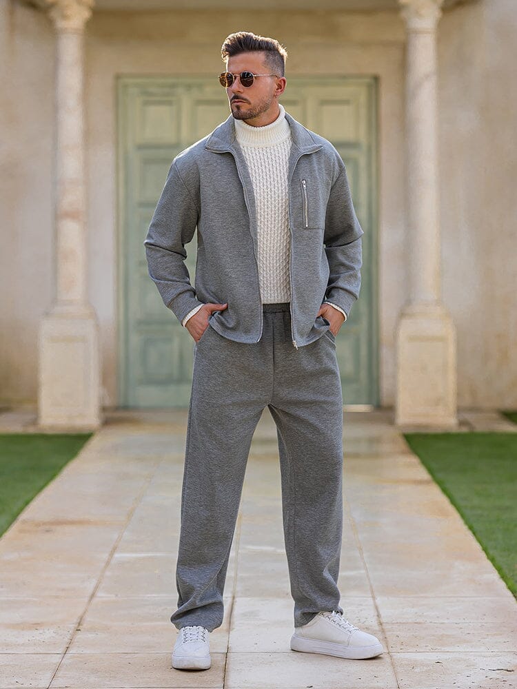 Man wearing a gray outfit standing in front of a building with green doors.