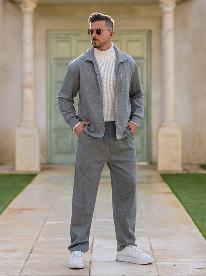 Man wearing a gray outfit standing in front of a building with green doors.