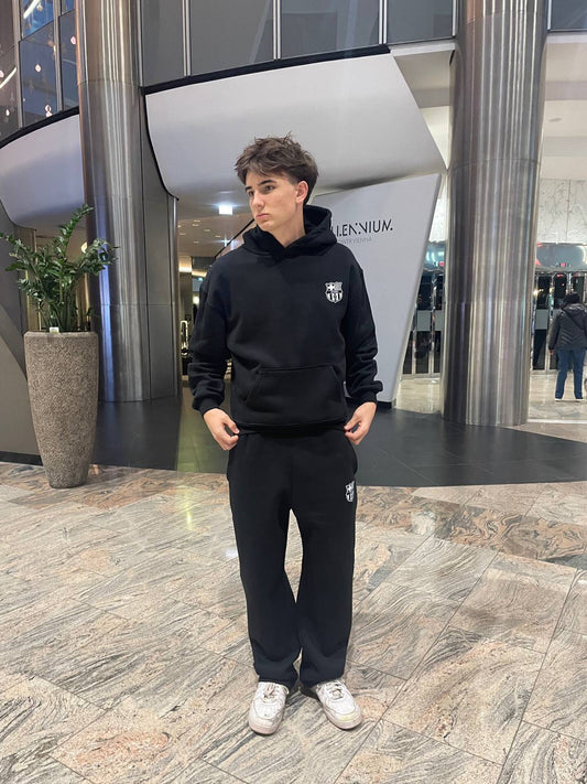 Person wearing a black hoodie and pants in a modern indoor setting