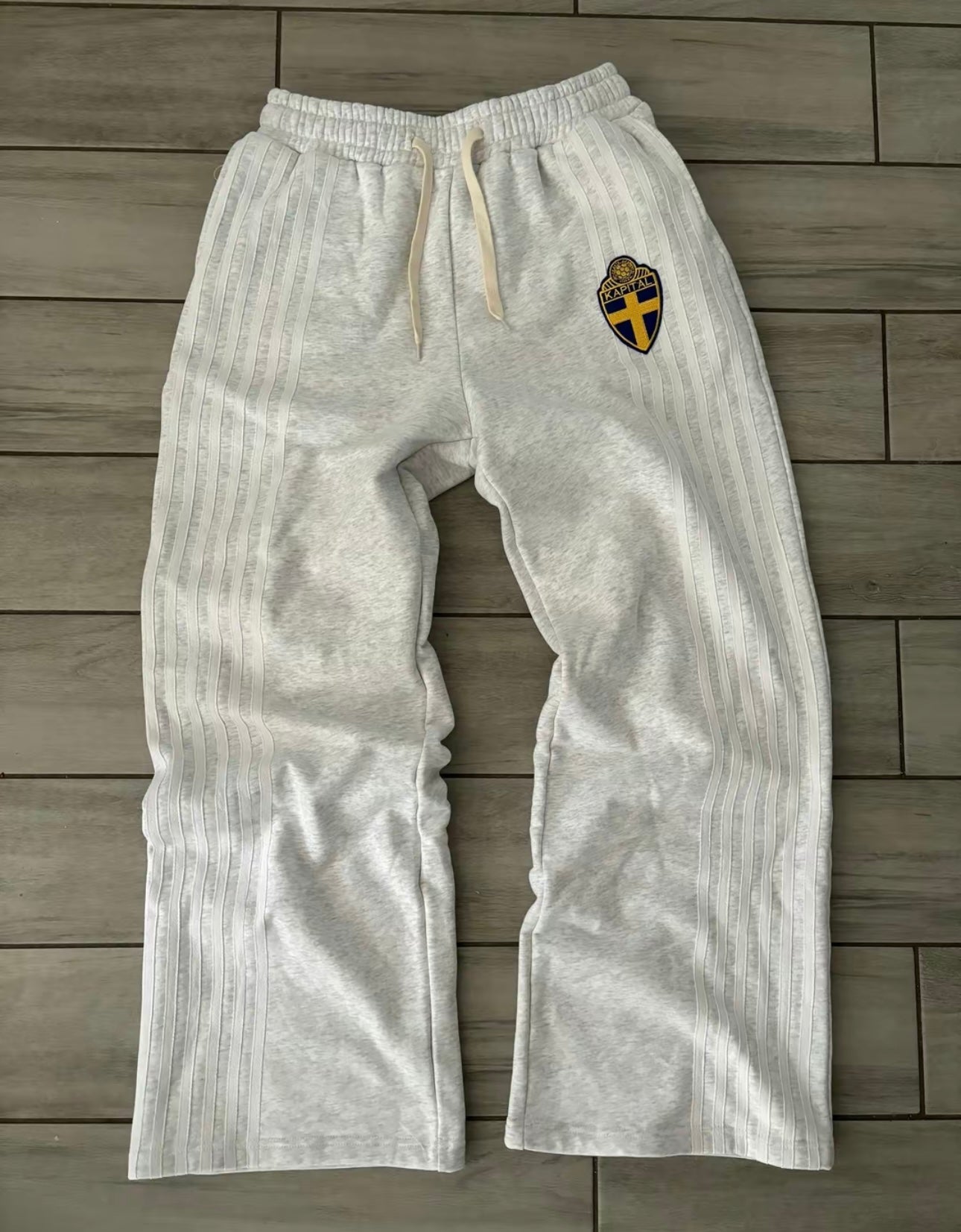 Light gray sweatpants with a logo on a wooden floor