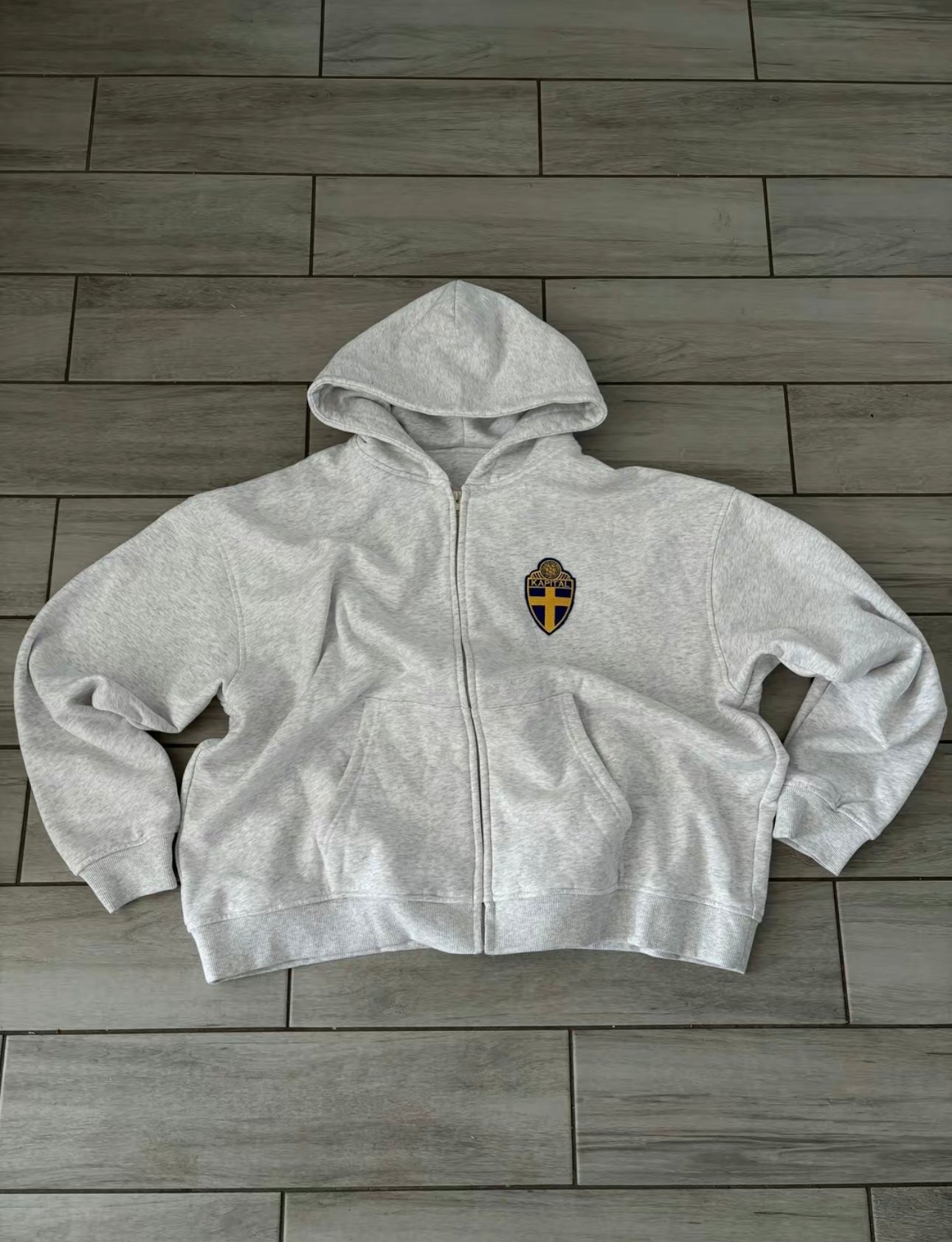 Gray hoodie with a logo on a wooden floor