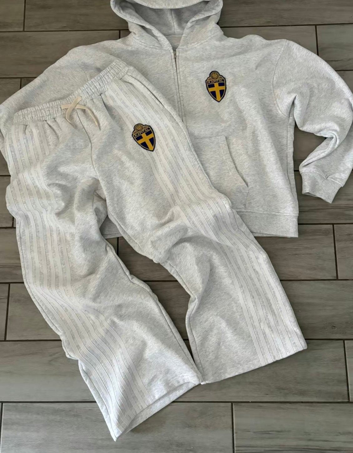 Gray tracksuit with logos on a wooden floor