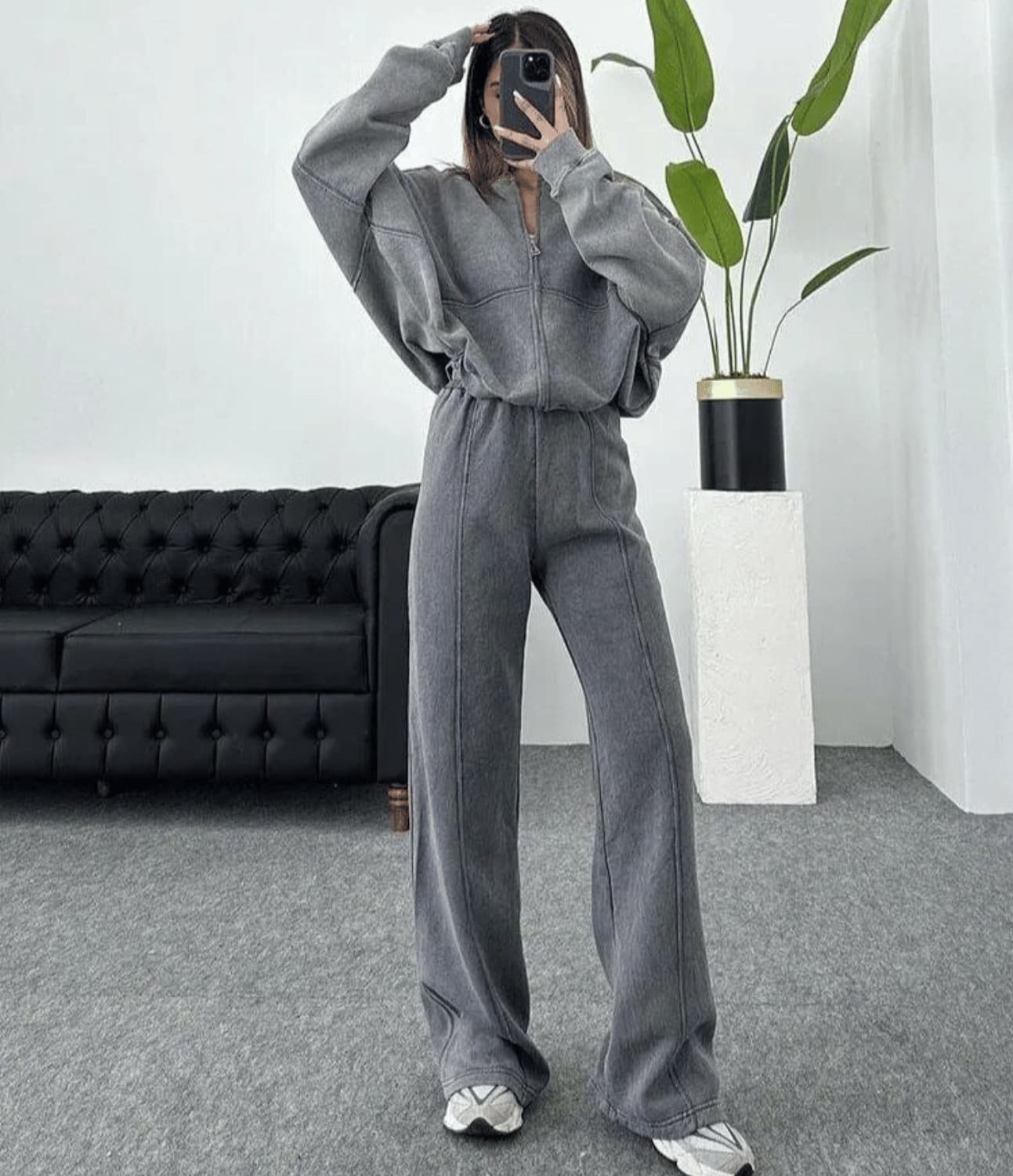 Person wearing a gray tracksuit in a modern living room.