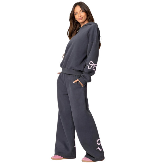 Woman wearing a dark gray sweatshirt and pants with a logo on a white background
