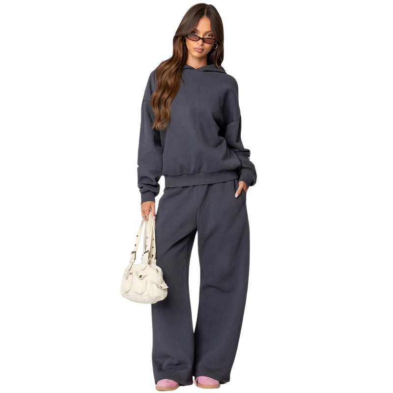 Woman wearing a gray tracksuit holding a white handbag on a white background