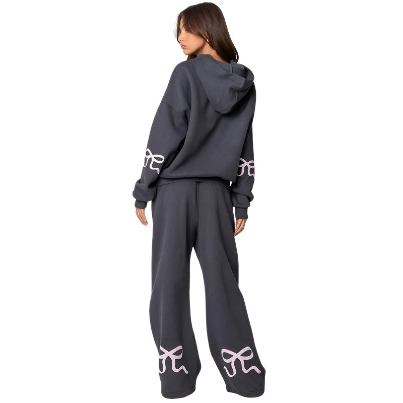 Person wearing a dark gray hoodie and pants with white designs on a white background