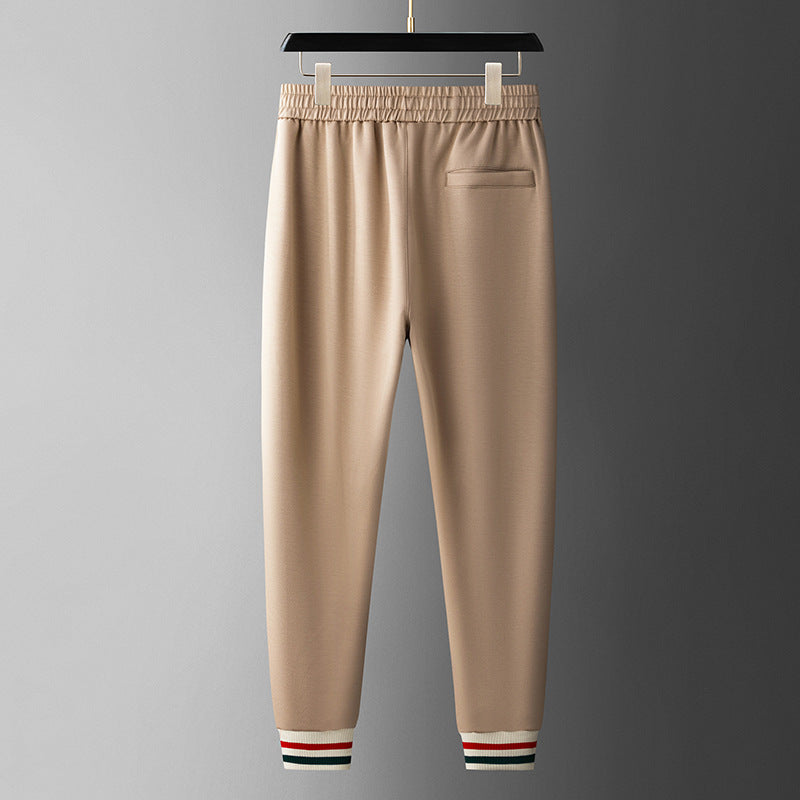 Beige sweatpants with striped cuffs on a gray background