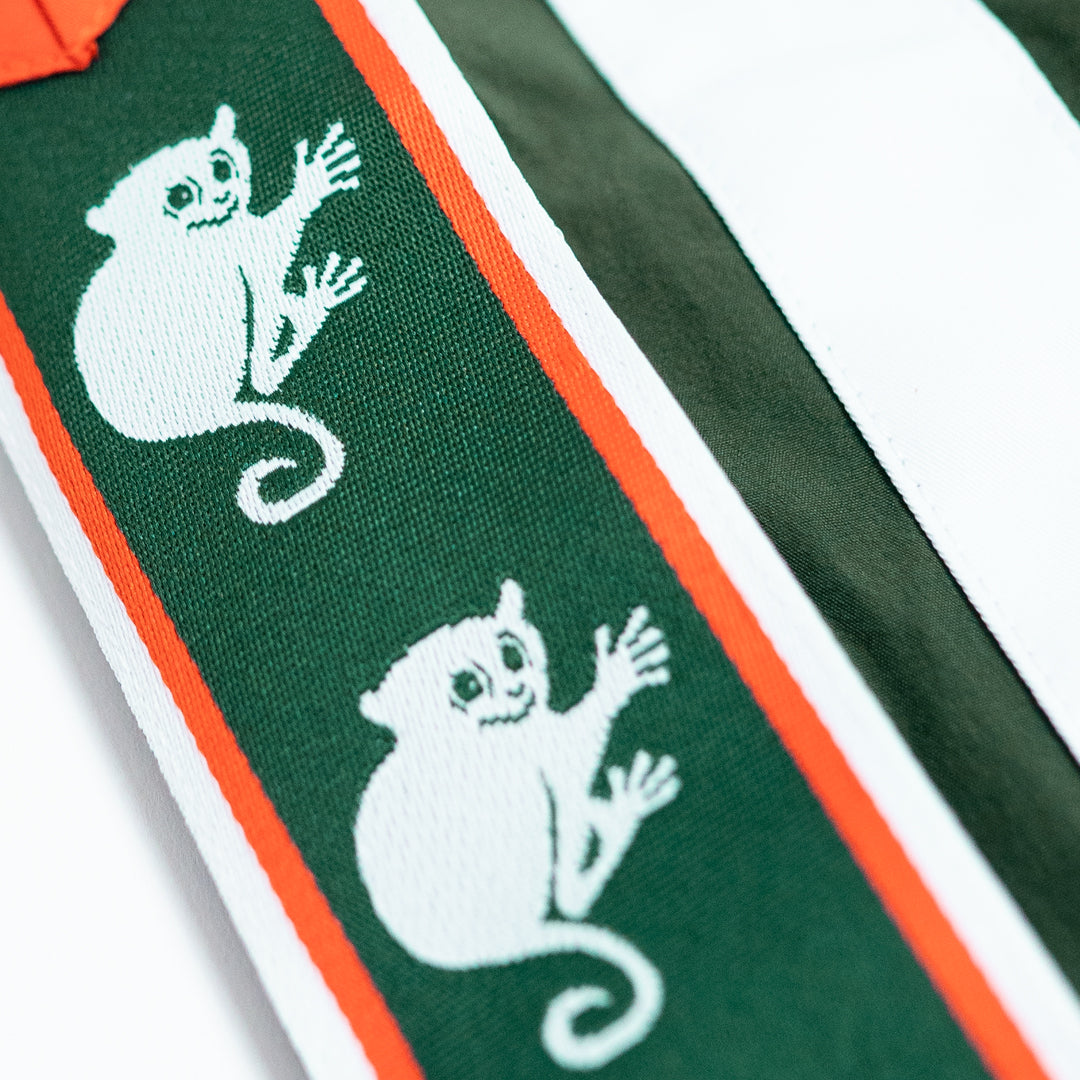 Close-up of a green fabric with embroidered white ghost designs and orange and white stripes.