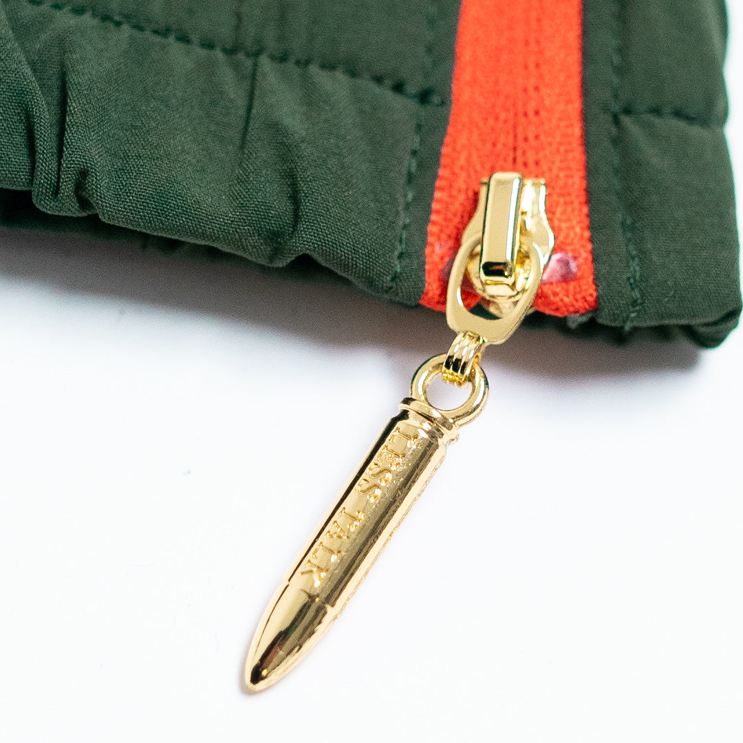 Gold zipper pull attached to a green jacket with an orange stripe on a white background