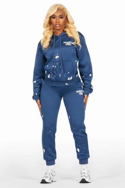 Woman wearing a blue hoodie and jogger set with white paint splatter design on a white background