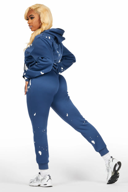 Woman wearing a blue tracksuit with white speckles on a white background