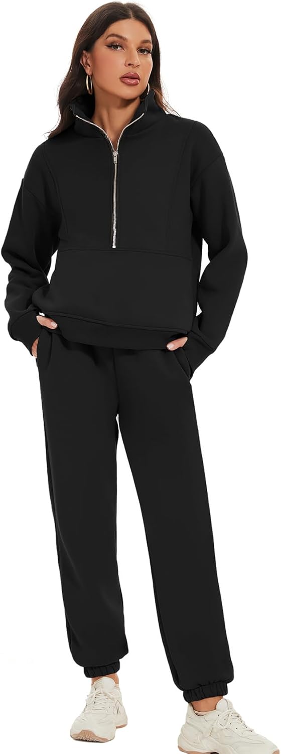 Woman wearing a black zip-up sweatshirt and pants with white sneakers on a white background