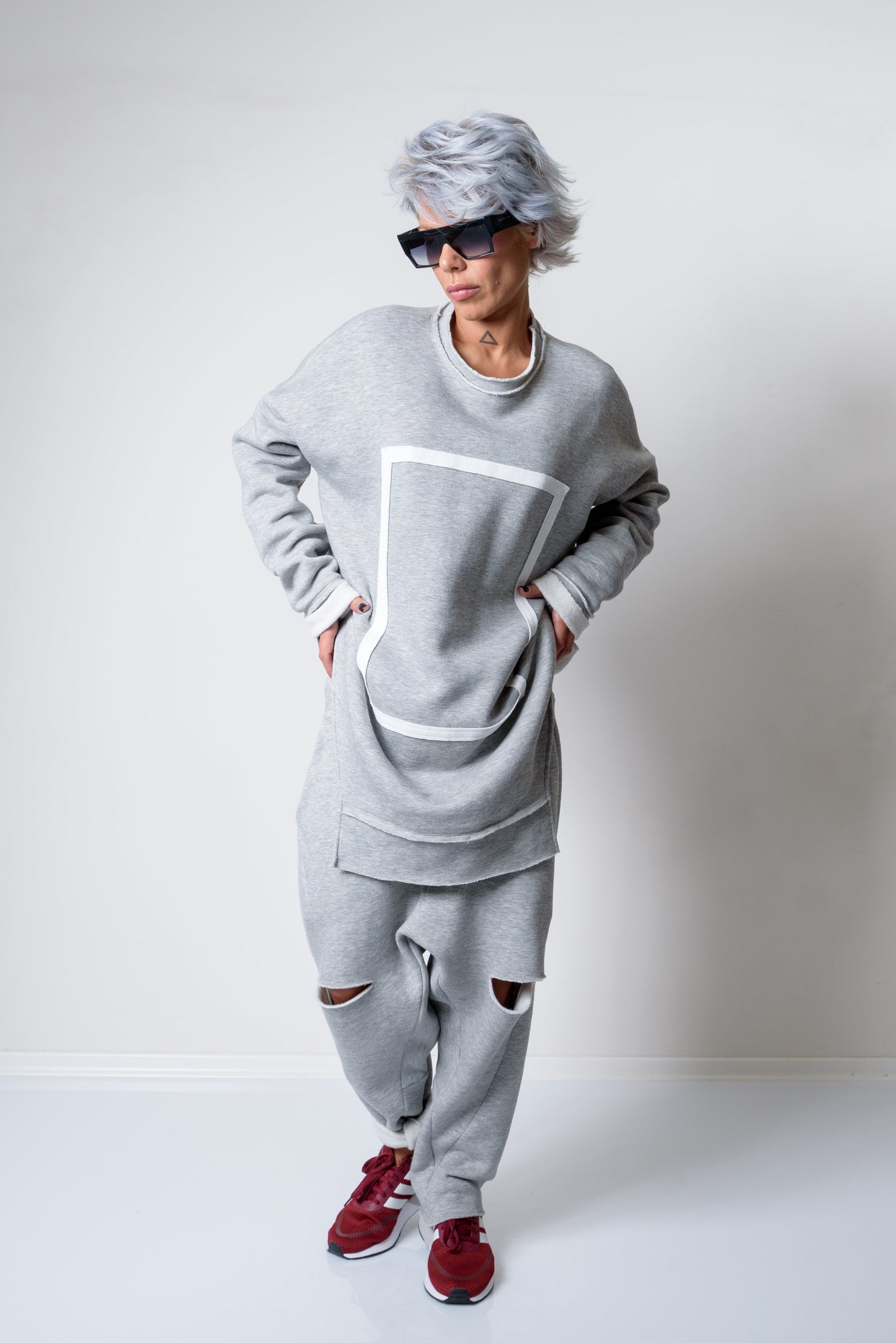 Person wearing a gray outfit with red shoes on a white background