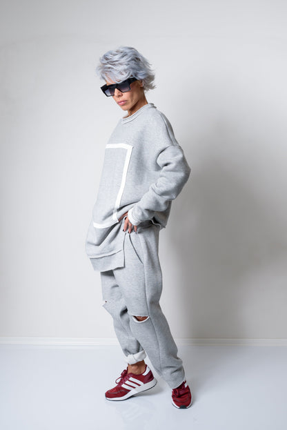 Person wearing a gray tracksuit with red sneakers on a white background
