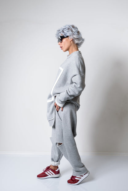 Person wearing a gray tracksuit with red Adidas sneakers on a white background