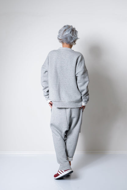 Person wearing a gray tracksuit with white walls and a white floor