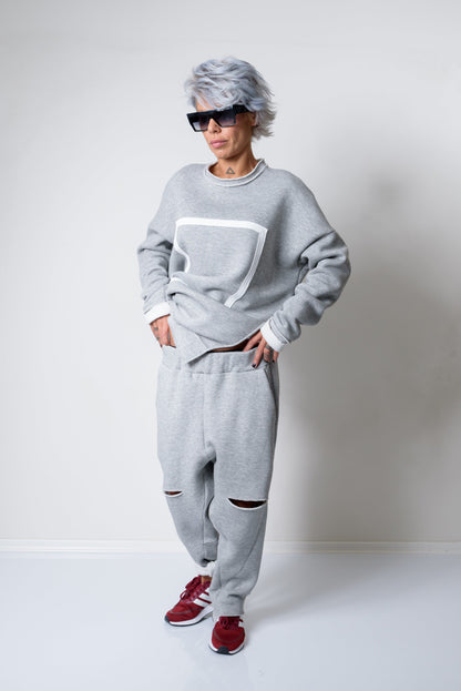 Person wearing a gray sweatshirt and pants with red shoes on a white background