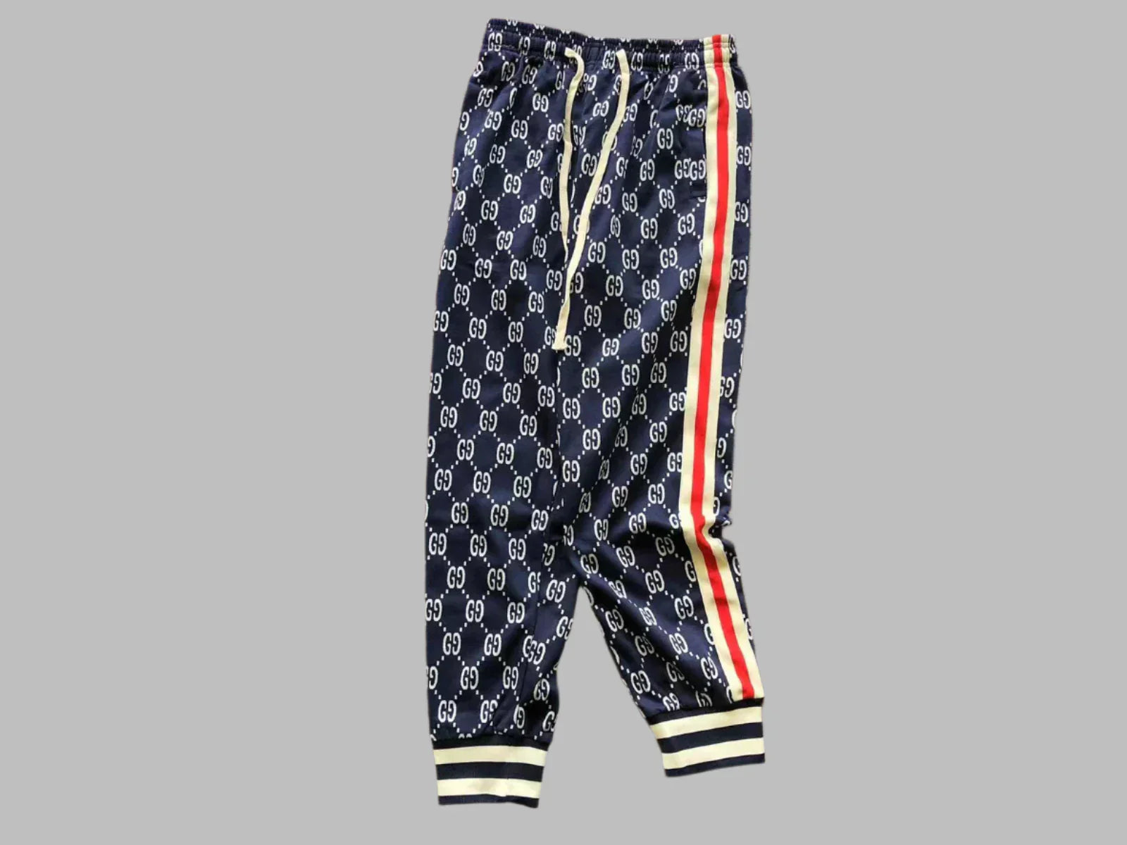 Navy blue pants with white logo pattern and red and yellow stripes on a gray background