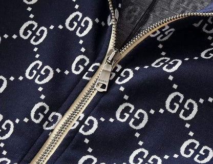 Close-up of a navy blue fabric with white 'GG' logo pattern and a gold zipper.