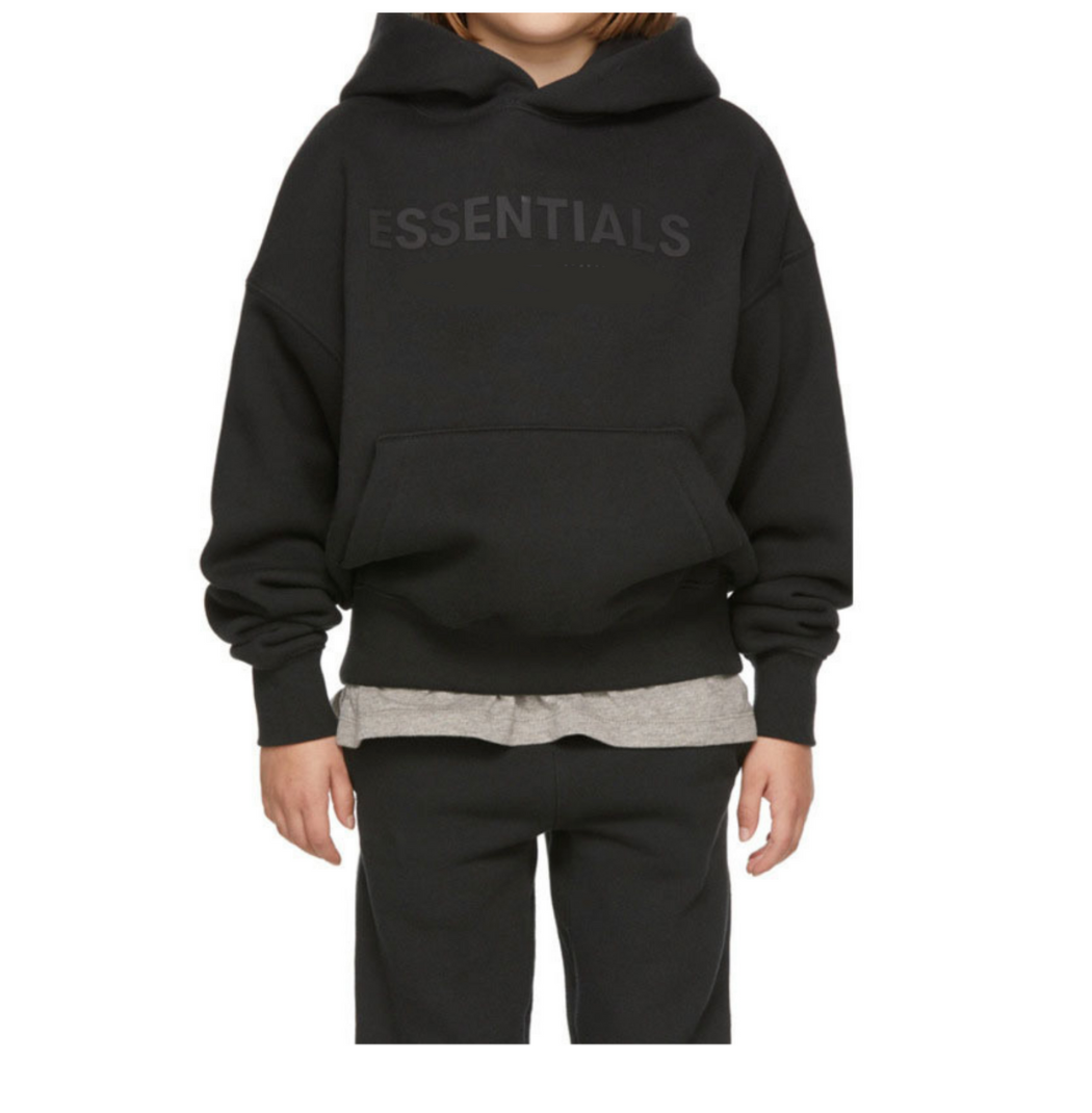 Person wearing a black hoodie with 'ESSENTIALS' text on a white background