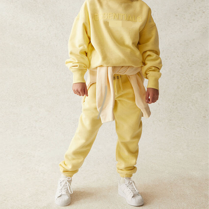 Person wearing a yellow tracksuit with white sneakers on a light background