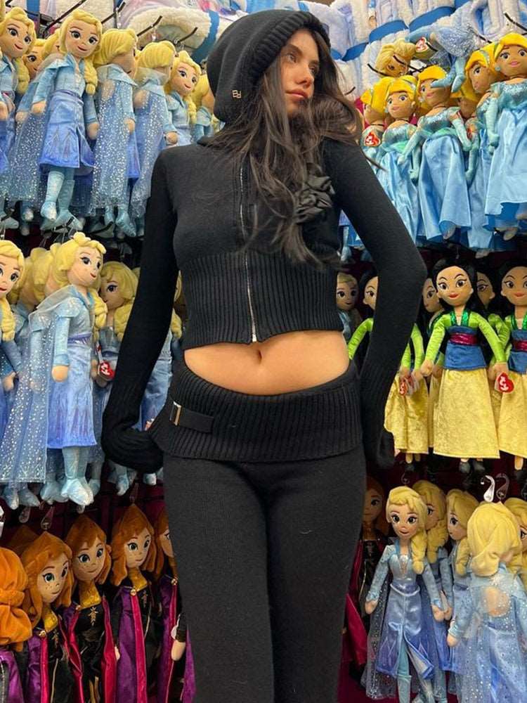 Person wearing a black outfit standing in front of a display of dolls.