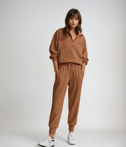 Woman wearing a brown tracksuit with white sneakers on a plain background