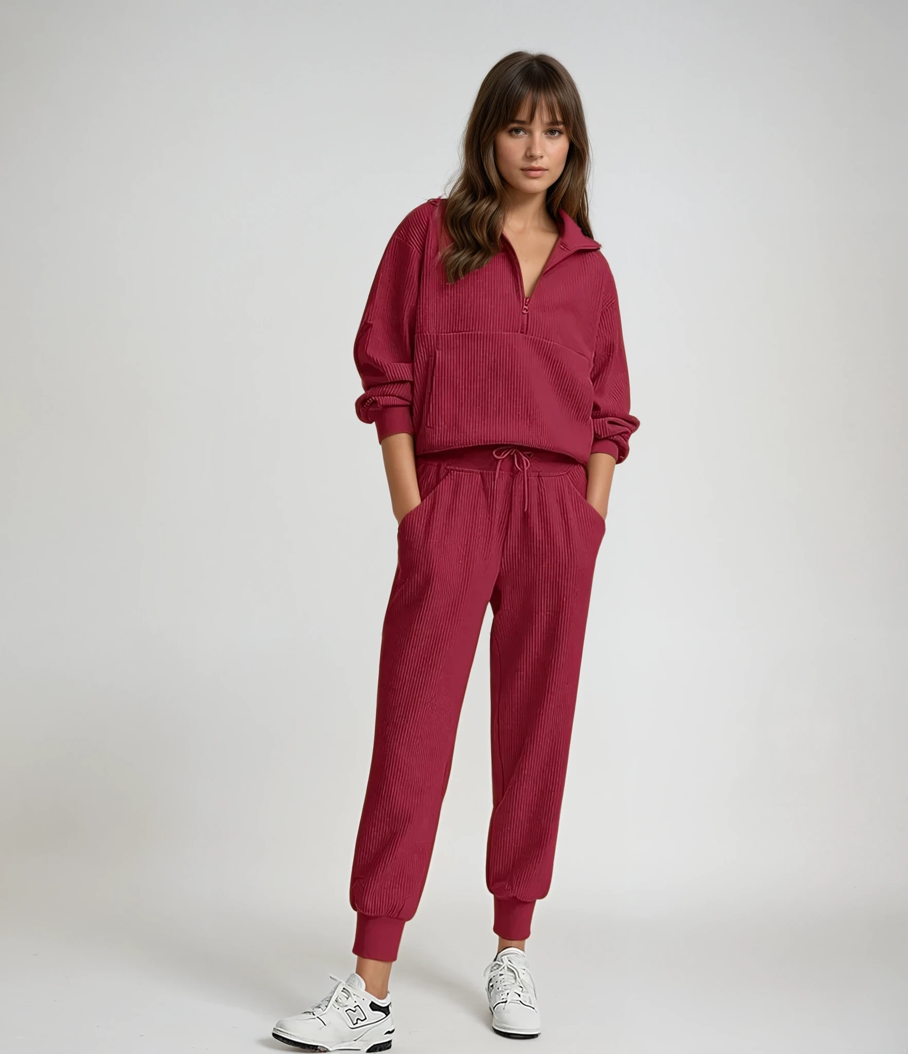 Woman wearing a red tracksuit with white sneakers on a plain background