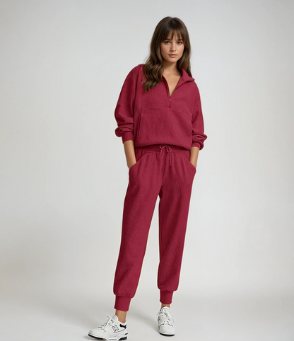 Woman wearing a red tracksuit with white sneakers on a plain background