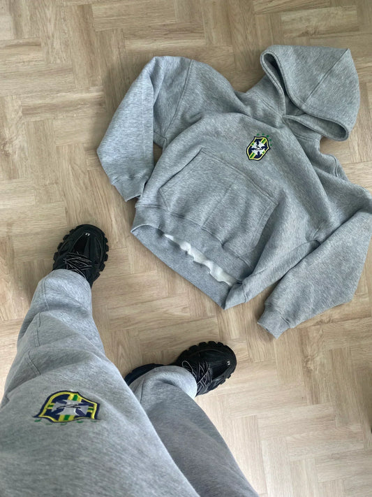 Gray hoodie and pants with a logo on a wooden floor