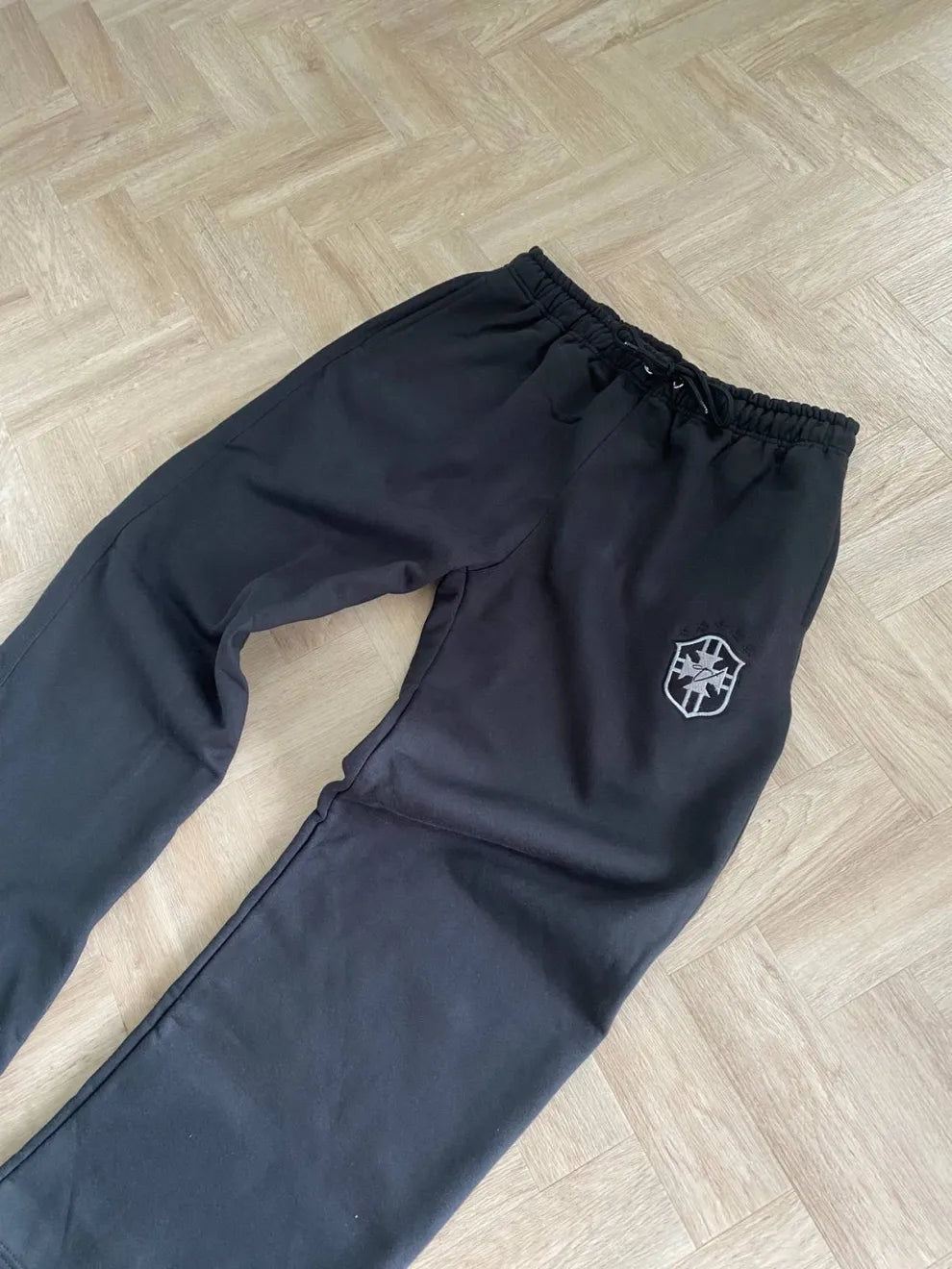 Black pants with a logo on a wooden floor