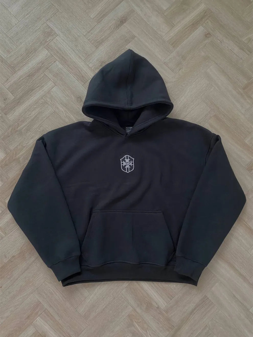 Black hoodie with a logo on a wooden floor