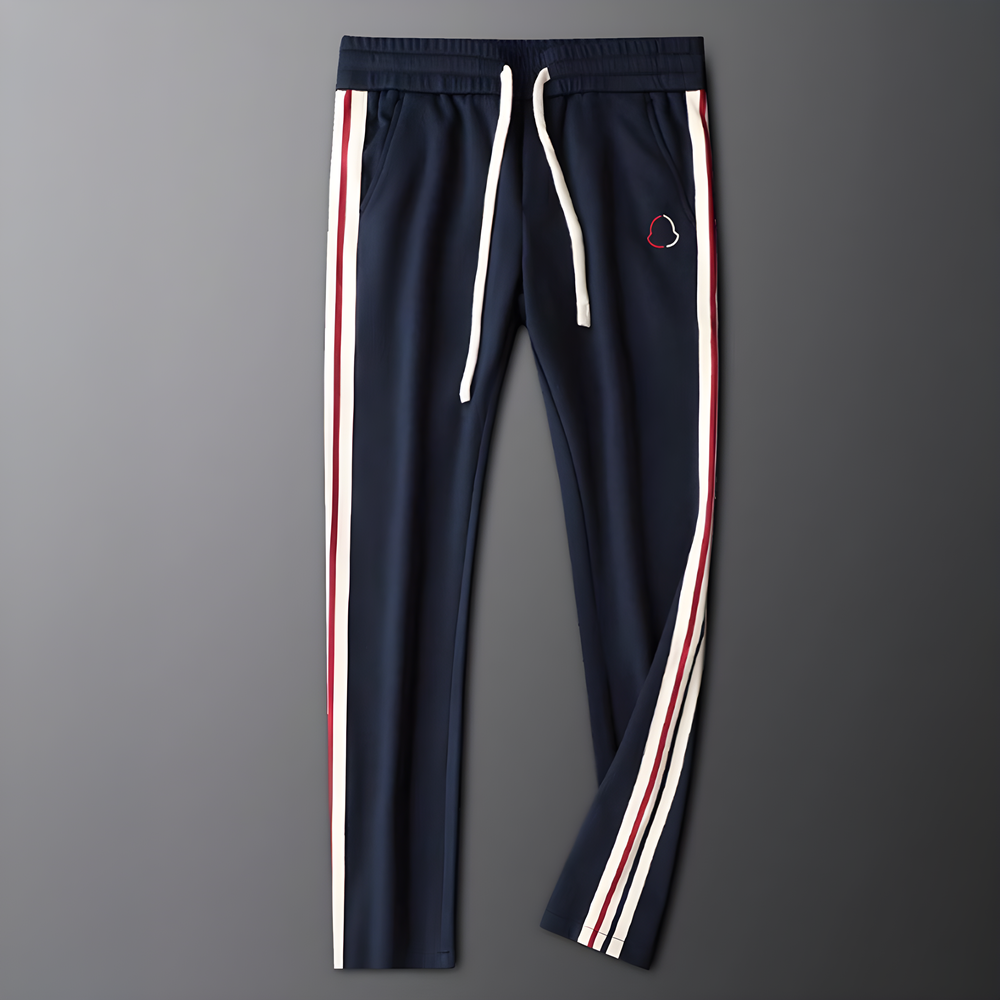 Navy blue track pants with white and red stripes on a gray background