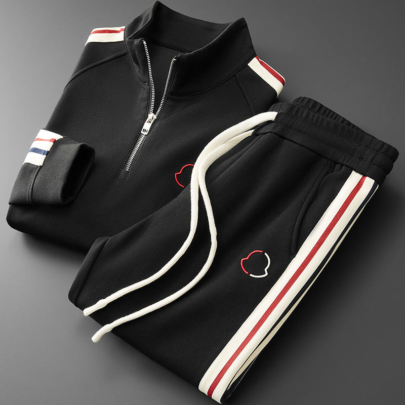 Black tracksuit with white, red, and blue accents on a gray background