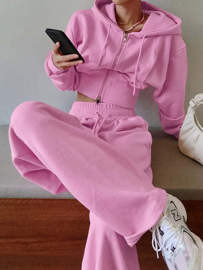Person wearing a pink tracksuit sitting on a wooden bench.