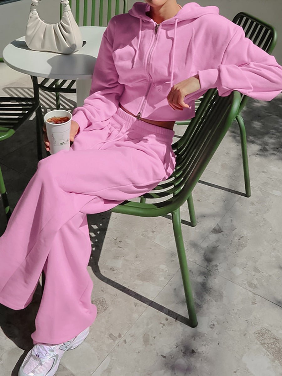 Person wearing a pink tracksuit sitting on a green chair outdoors.