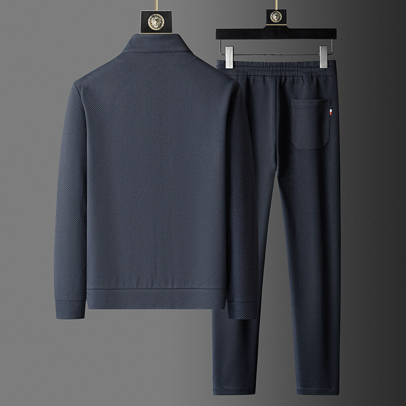 Navy blue tracksuit on hangers against a gray background