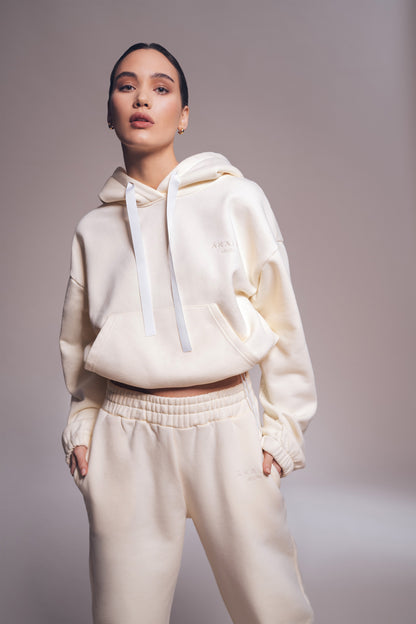 Person wearing a cream-colored hoodie and pants against a plain background