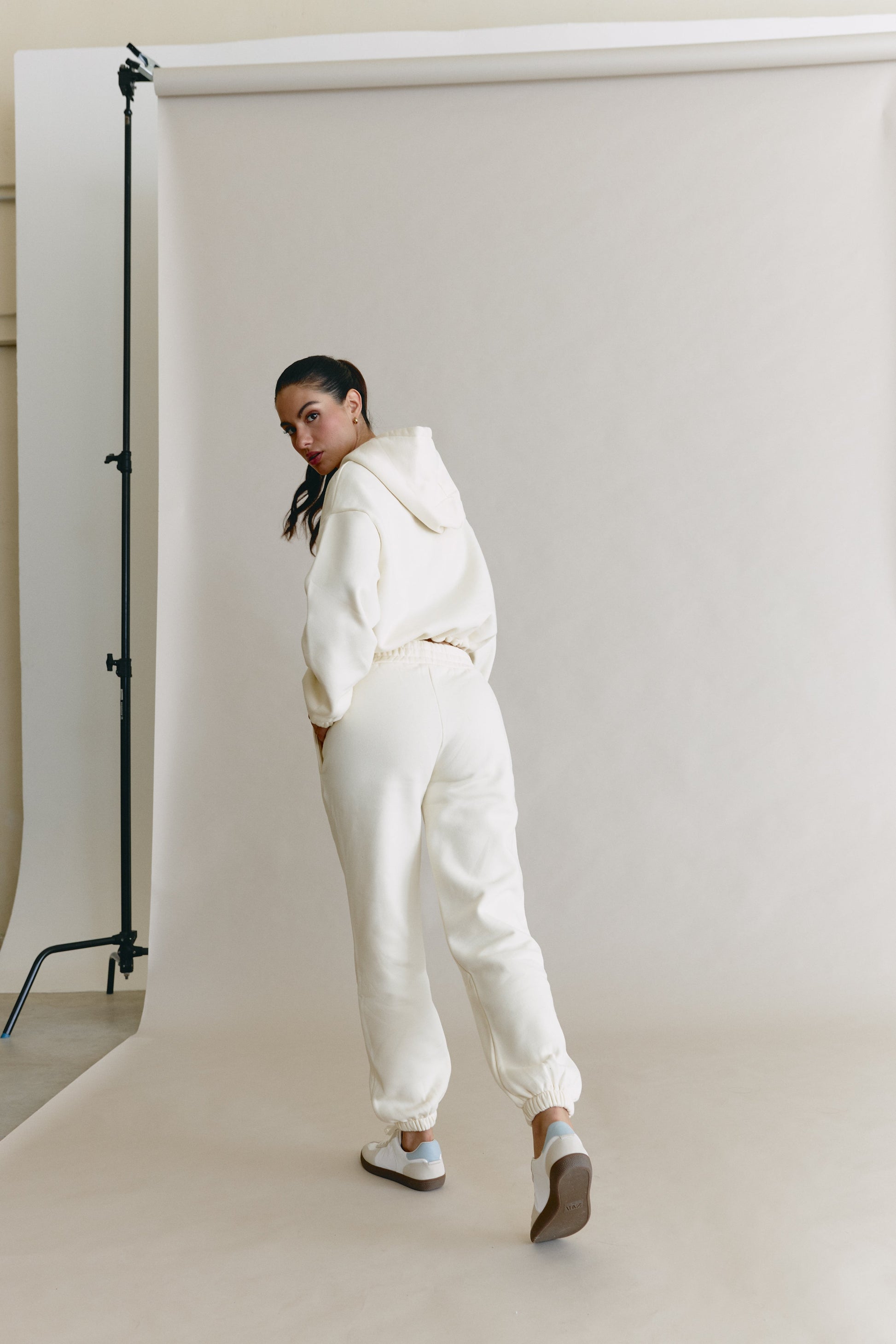 Person wearing a white outfit standing in front of a white backdrop