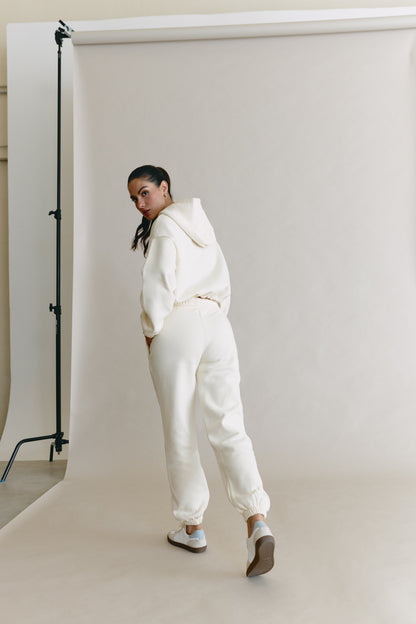 Person wearing a white outfit standing in front of a white backdrop