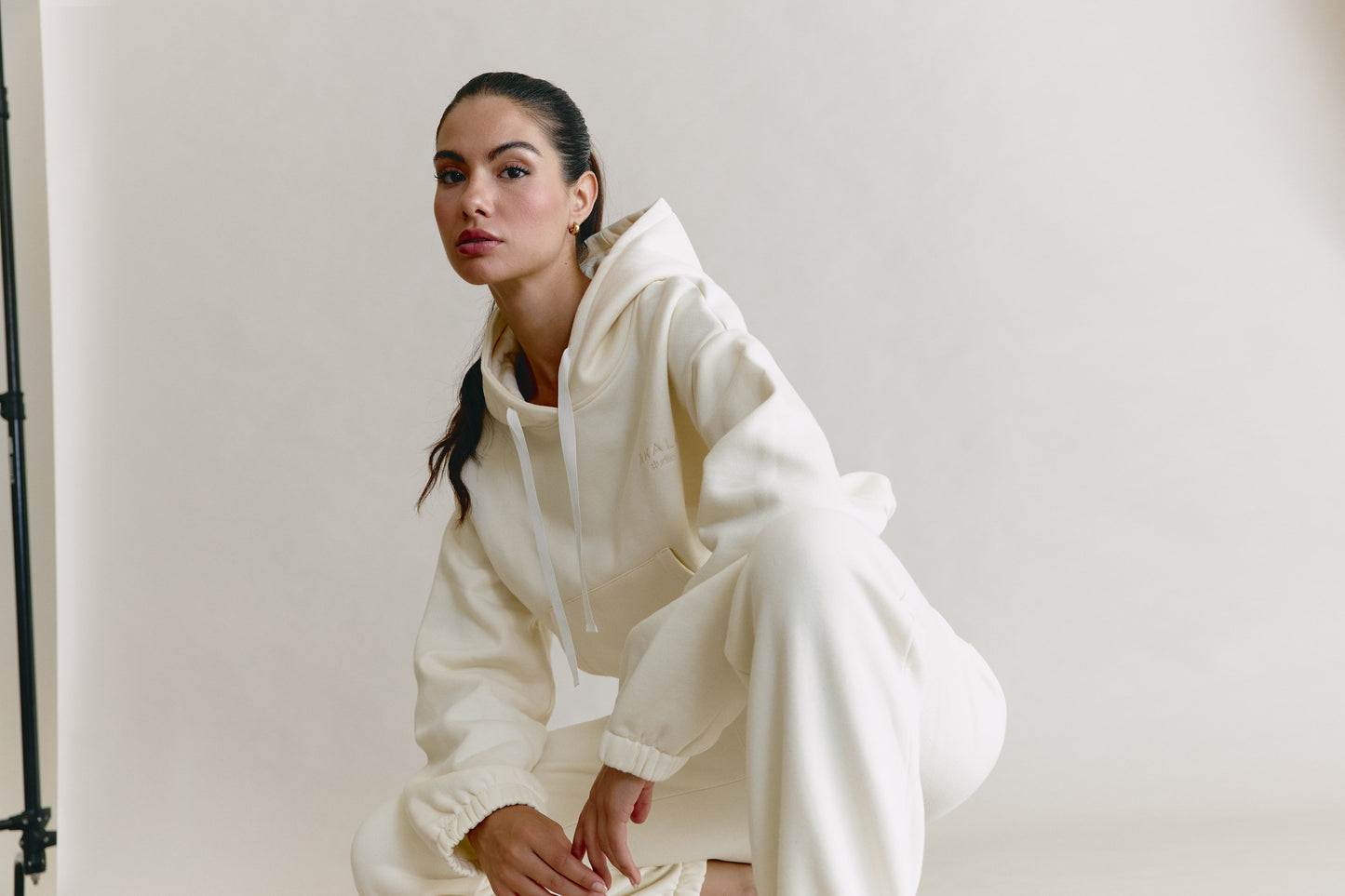 Woman wearing a white outfit sitting against a plain background